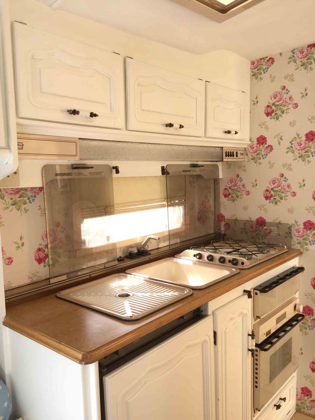 Dolly the caravan's kitchen area; after it had been painted as part of my first caravan makeover. I painted the units white and wallpapered the wall's with Cath Kidston wallpaper. More info on both of my caravan makeovers on the blog!